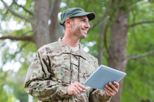 Soldat ser på tablett pc i parken – stockfoto