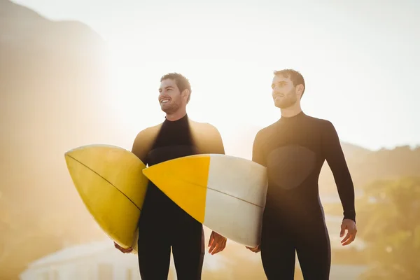 Mannen in wetsuits met surfboard op strand — Stockfoto