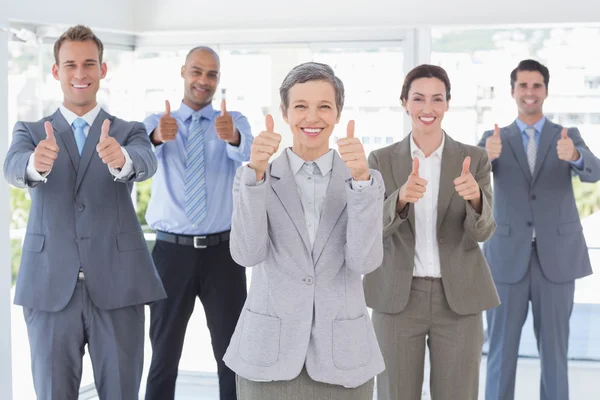 Equipo de negocios sonriendo a la cámara mostrando los pulgares hacia arriba — Foto de Stock