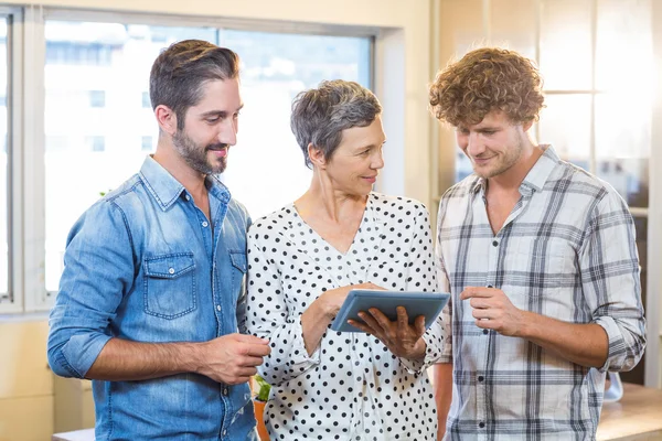 Smiling business team looking together at tablet — Stock Photo, Image