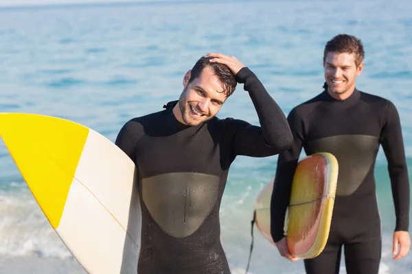 Män i våtdräkter med surfbräda på stranden — Stockfoto