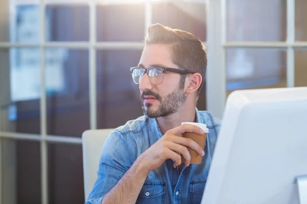 Casual businessman sitting at desk and holding coffee — Stock Fotó