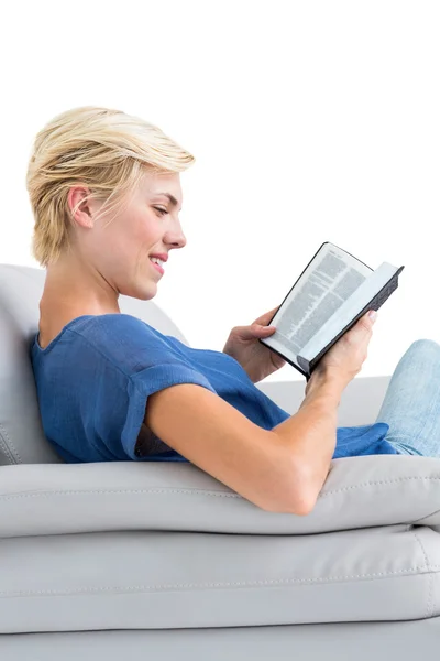 Ξανθιά γυναίκα που διαβάζει το βιβλίο στον καναπέ — Φωτογραφία Αρχείου