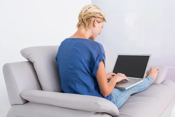 Blonde vrouw met laptop op Bank — Stockfoto