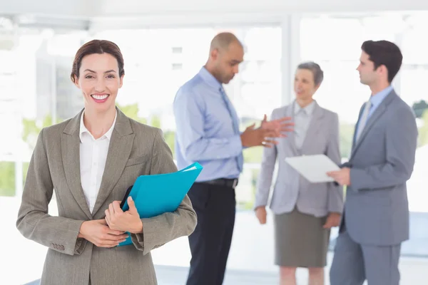 Smiling businesswoman holding files and looking at camera — Stock Photo, Image