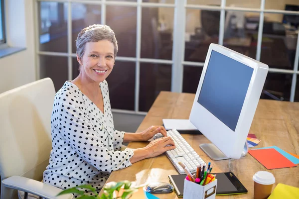 Улыбающаяся деловая женщина, печатающая на клавиатуре — стоковое фото