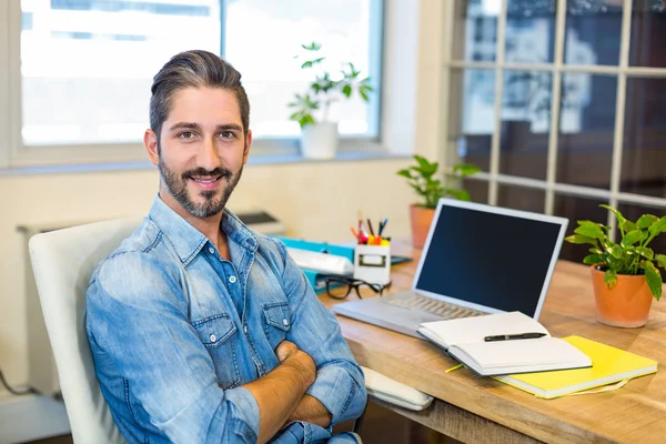 Businessman sitting at desk arms crossed — Stock fotografie