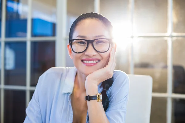 Mujer de negocios sonriente sentada en su escritorio —  Fotos de Stock