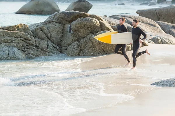 Män i våtdräkter med surfbräda på stranden — Stockfoto