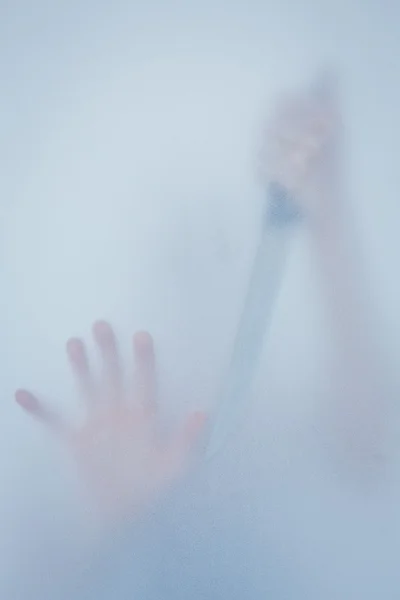 Hand touching frosted glass and holding knife — Stock Photo, Image