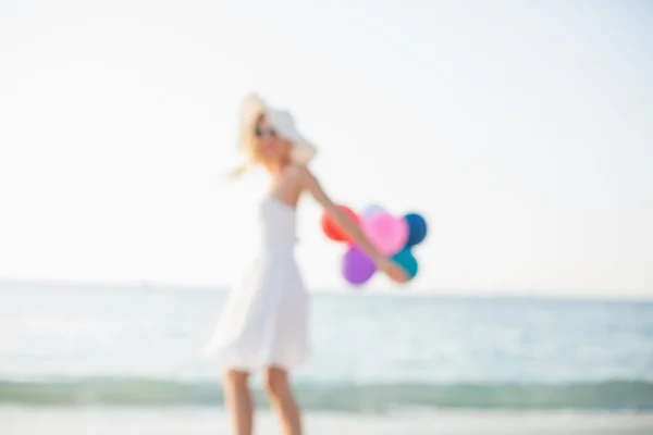 Woman holding baloons at beach — Stock fotografie