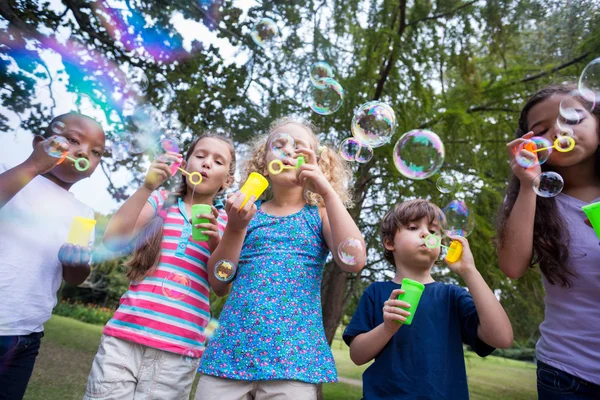 Pequeños amigos soplando burbujas en el parque — Foto de Stock