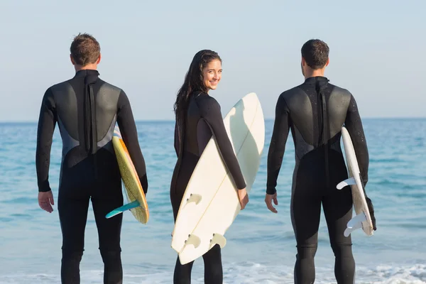 Vänner på våtdräkter med surfbräda på stranden — Stockfoto