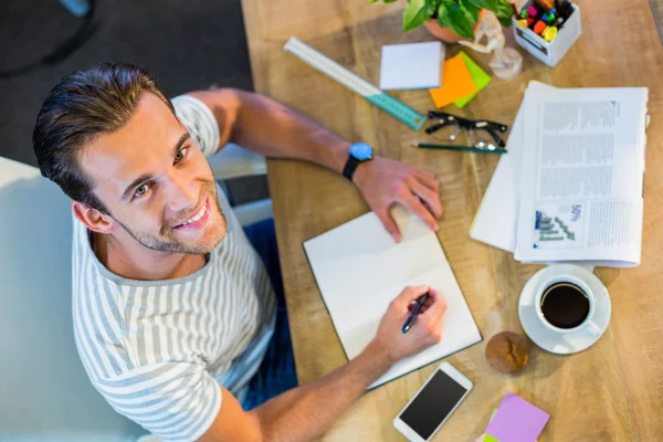 Souriant homme d'affaires occasionnel écrit dans le bloc-notes — Photo