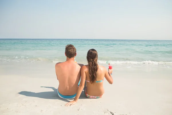 Couple drinking cocktails at beach — Stockfoto