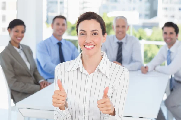 Sorrindo empresária dando polegares com sua equipe atrás — Fotografia de Stock