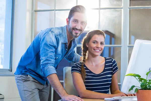 Colegas sorridentes trabalhando juntos no computador — Fotografia de Stock