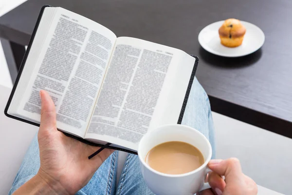 Frau liest Buch und hält Tasse — Stockfoto