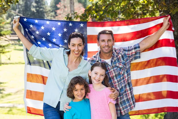 Familia feliz sonriendo con una bandera americana en un parque Fotos de stock