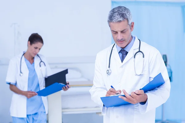 Male and female doctors working on reports — Stock Photo, Image