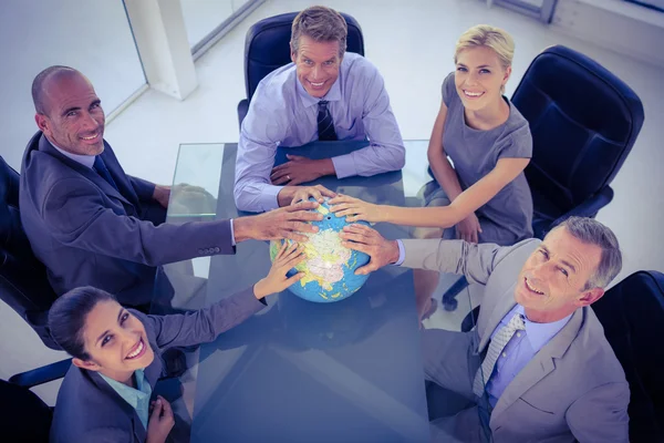 Business team putting hands on globe — Stock Photo, Image