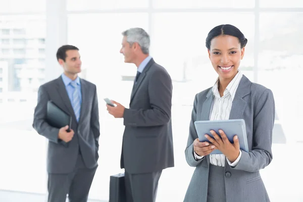 Femme d'affaires utilisant une tablette avec des collègues derrière dans le bureau — Photo