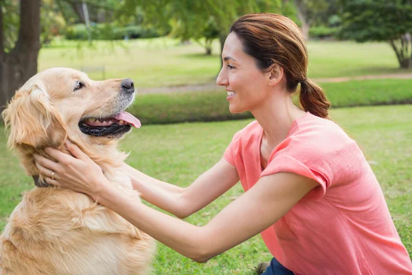 Pretty brunette with her dog in the park — Stock Photo, Image