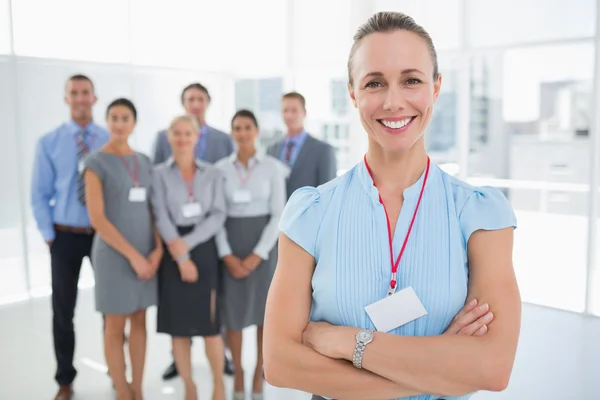 Geschäftsfrau lächelt mit Team im Rücken in die Kamera — Stockfoto