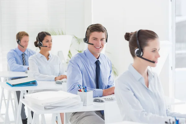 Equipe de negócios trabalhando em computadores e usando headsets — Fotografia de Stock