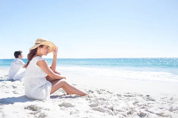 Brünette sitzt im Sand und schaut auf das Meer — Stockfoto