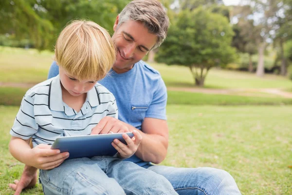 Щасливий батько зі своїм сином використовує планшет у парку — стокове фото