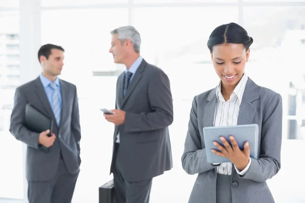 Empresaria usando una tableta con colegas detrás — Foto de Stock