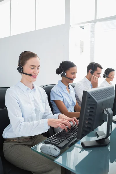 Pessoas de negócios com fones de ouvido usando computadores — Fotografia de Stock