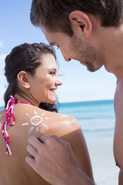 Knappe man zijn vriendin te zetten in de zon tan lotion — Stockfoto