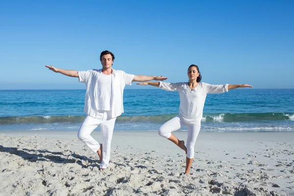 Pareja feliz haciendo yoga al lado del agua — Foto de Stock