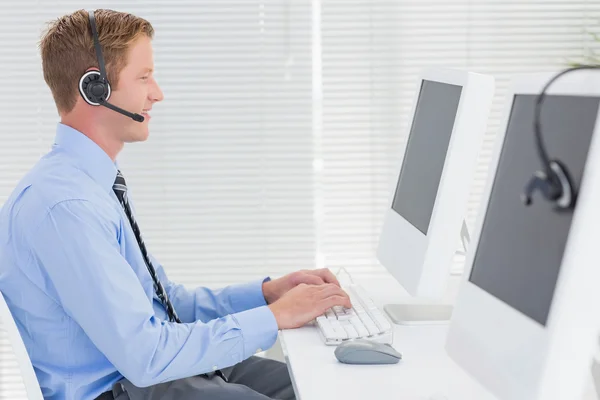 Agente guapo con auriculares escribiendo en el teclado — Foto de Stock