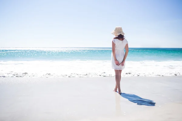 Pretty brunette wearing straw hat and walking in the water — Stock Photo, Image
