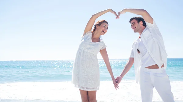 Happy couple forming heart shape with their hands — Stock Photo, Image