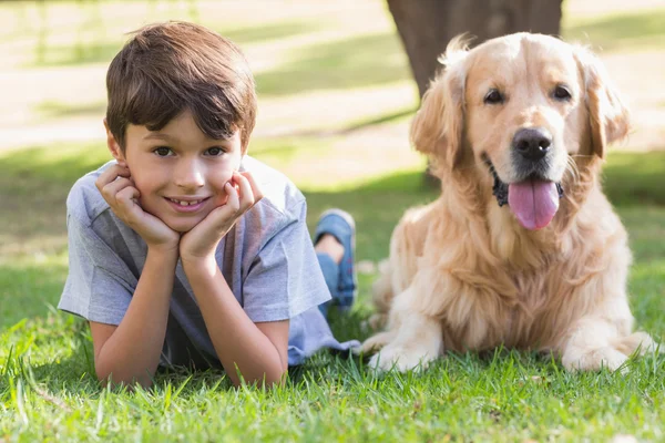 Kleine jongen op zoek naar camera met zijn hond in het park — Stockfoto