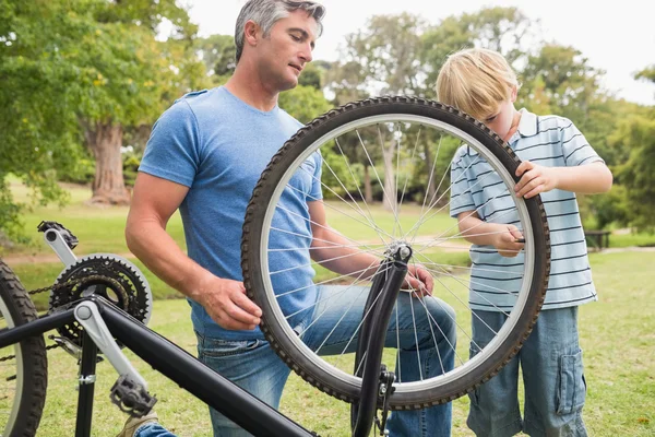 Far och hans son fastställande en cykel — Stockfoto