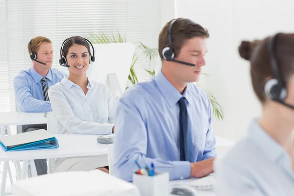 Equipe de negócios trabalhando em computadores e usando headsets — Fotografia de Stock