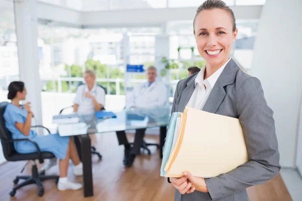 Femme d'affaires souriante tenant des fichiers et regardant la caméra — Photo