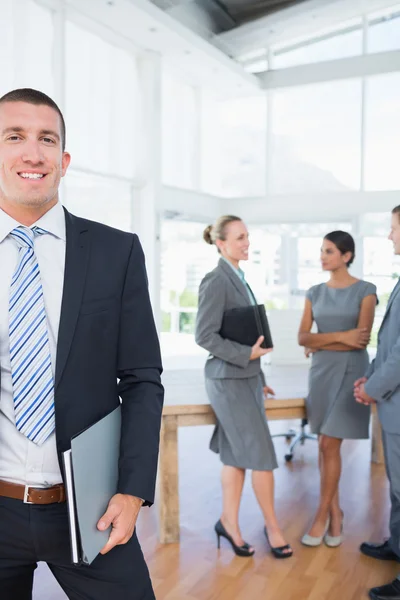 Empresario sonriendo con colegas detrás de él —  Fotos de Stock