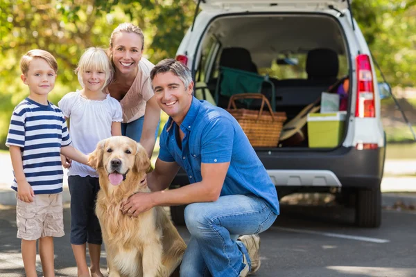 Glückliche Familie lächelt mit Hund in die Kamera — Stockfoto