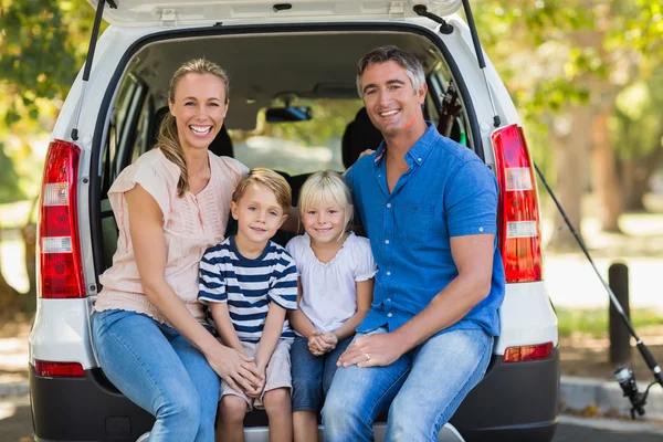 Família feliz de quatro sentados no tronco do carro — Fotografia de Stock