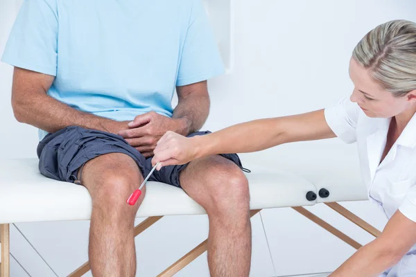 Lekarz sprawdzenie odruchów kolana jej pacjenta — Zdjęcie stockowe