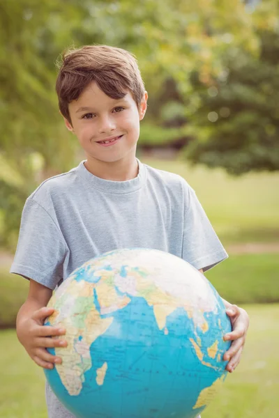 Ragazzo sorridente che tiene un globo terrestre nel parco — Foto Stock