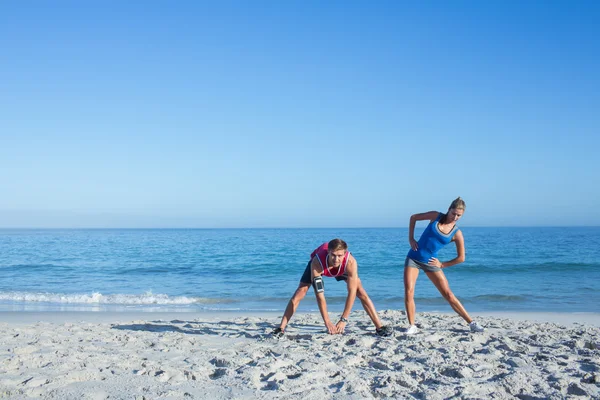 Lyckliga par stretching tillsammans vid vattnet — Stockfoto