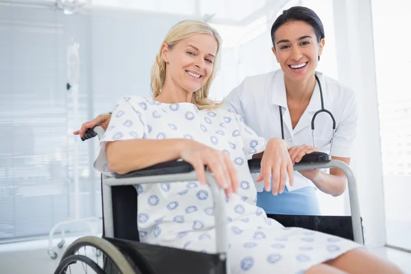 Arzt und Patient im Rollstuhl lächeln in die Kamera — Stockfoto