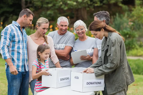 Vrijwilligers en gelukkige familie scheiden donaties voeders — Stockfoto